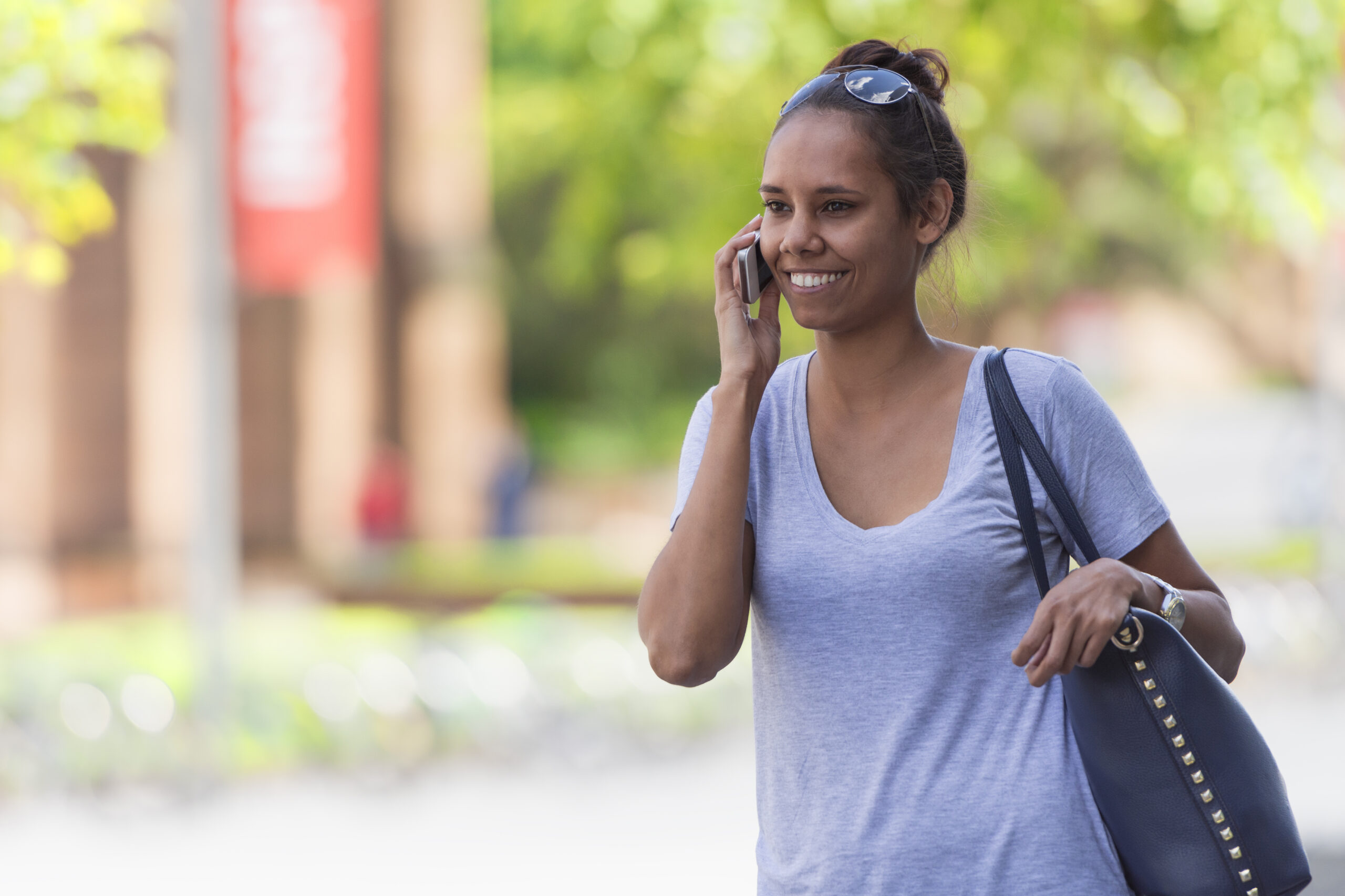 Color image of a young Australian Aboriginal woman calling with her smart phone. Copy space on left.